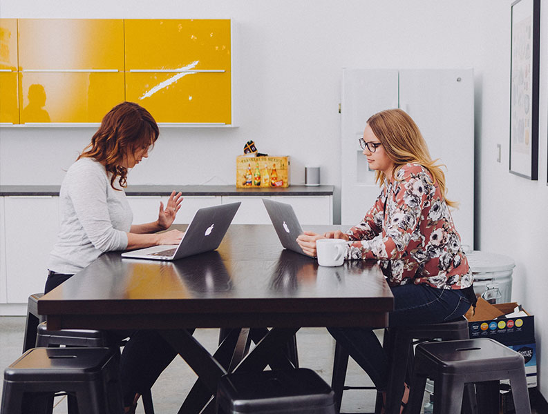 Two women using laptops and mobility software for enterprise mobile device management